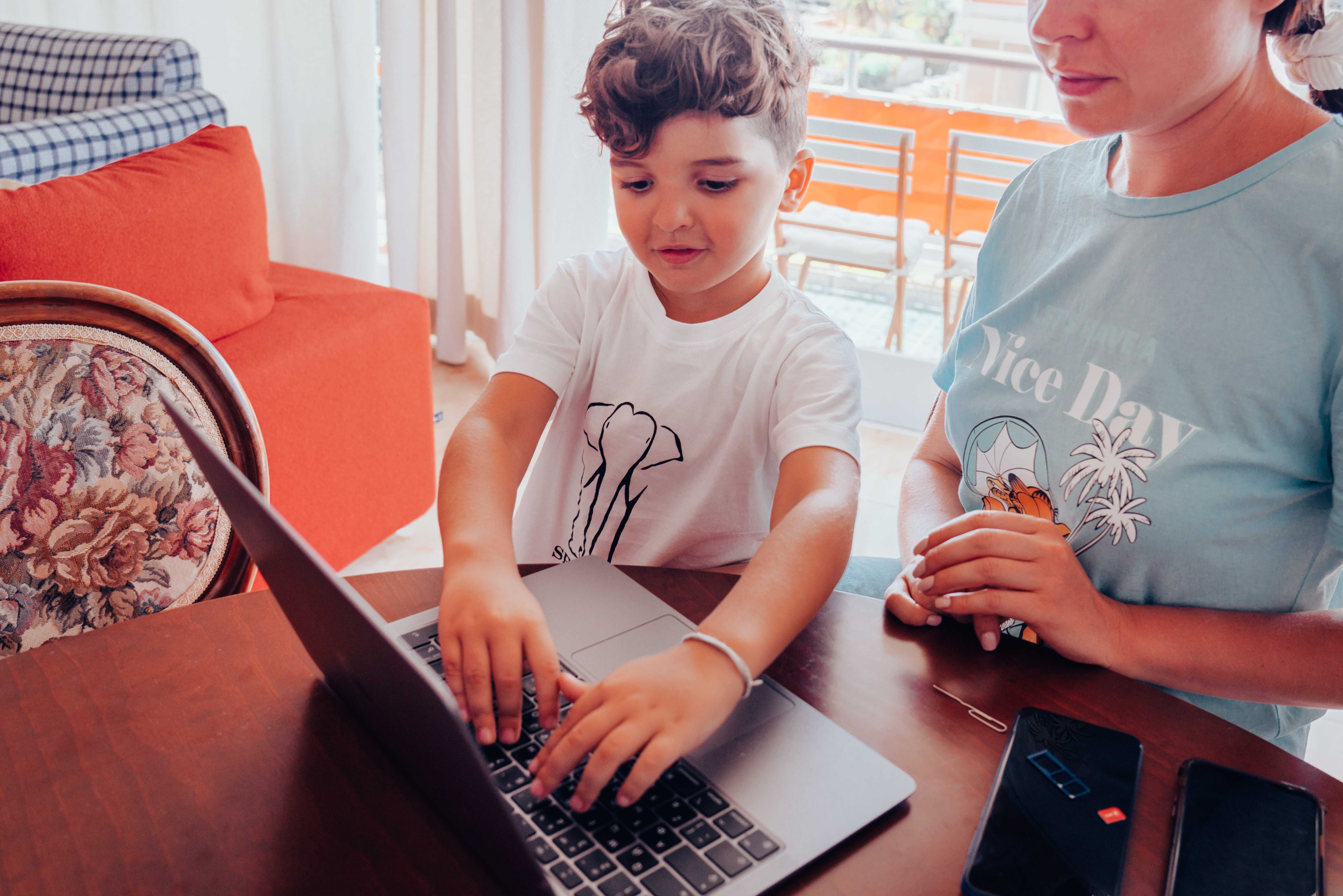 Adulto acompañando a una niña durante una experiencia de aprendizaje digital con ordenador